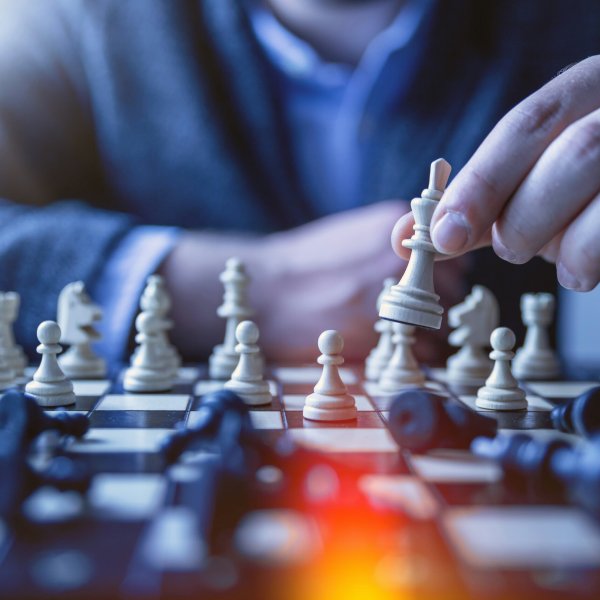 Performance Une personne en train de jouer aux échecs, capturée en train de déplacer une pièce sur un échiquier, avec une mise au point sélective sur la main et la pièce.
